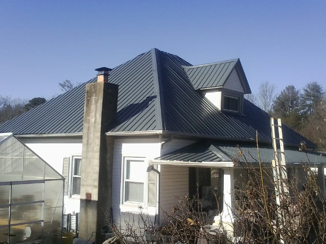 Dark blue standing seam metal roof on a white farmhouse with dormer — Slate & Tile Roof Repair by Roofing Brothers in Tracy