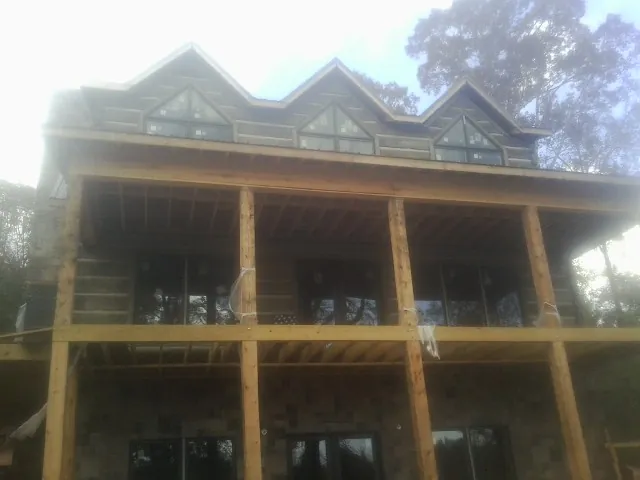 Dormers and porch framing on a large log home under construction — Roof Coating work by our crew in Tracy